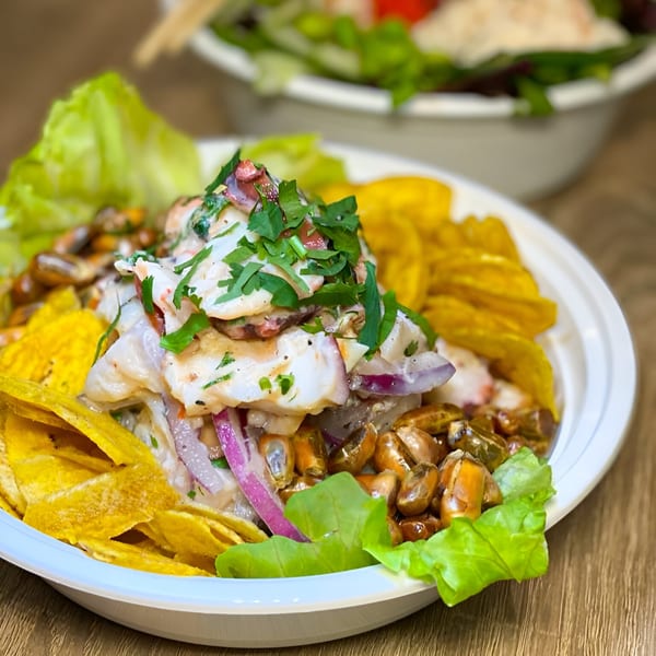 Close-up of a Poki Bowl with fish, red onions, plantain chips, corn, and lettuce.